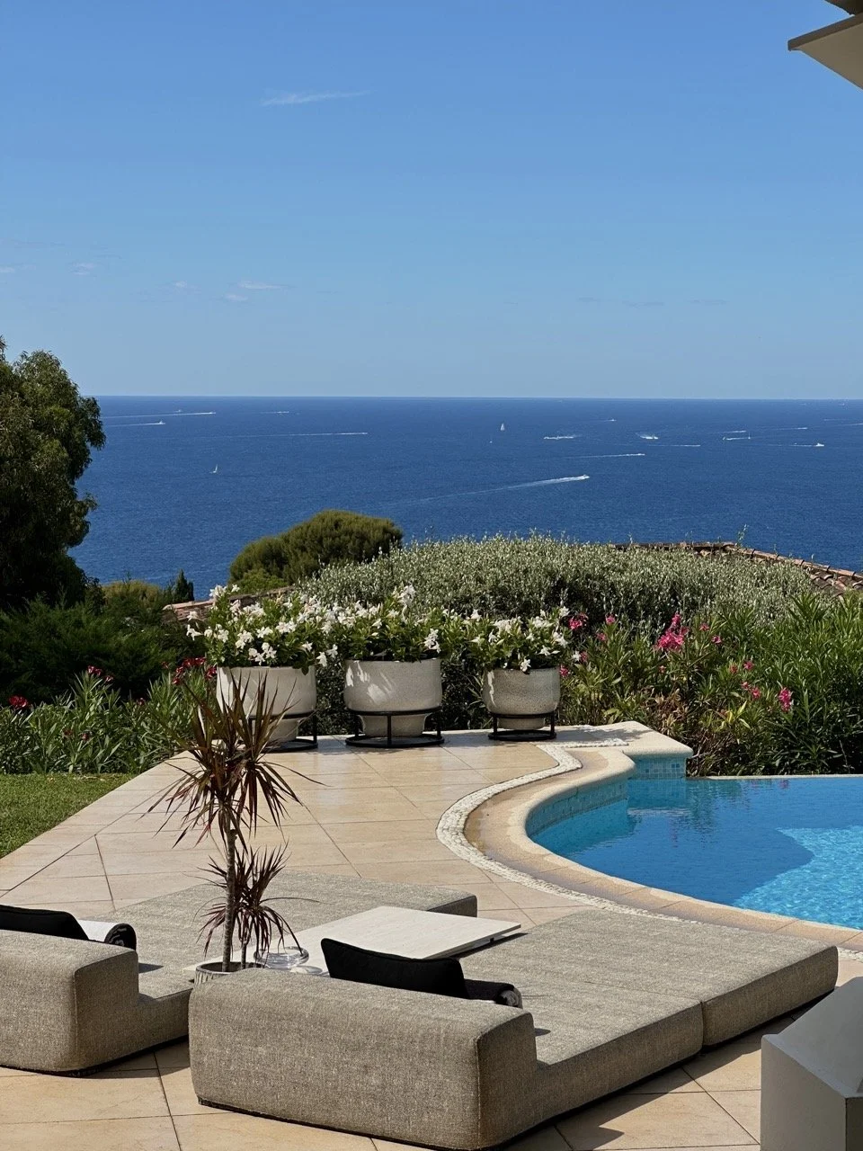 The Villa Monaco terrace and infinity pool with the Mediterranean beyond, small yachts visible on the horizon during show week