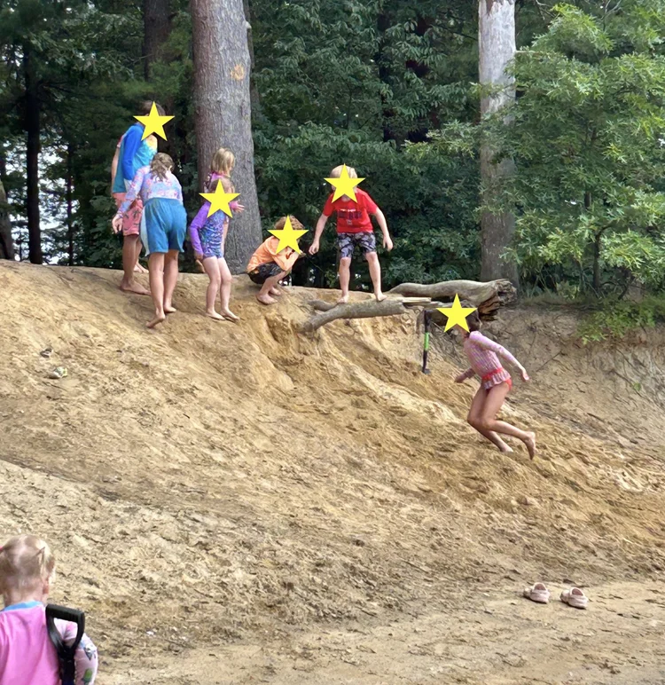 Children exploring a sandy riverbank during summer.