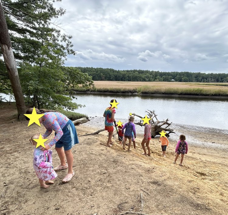 Children exploring a sandy riverbank during summer.