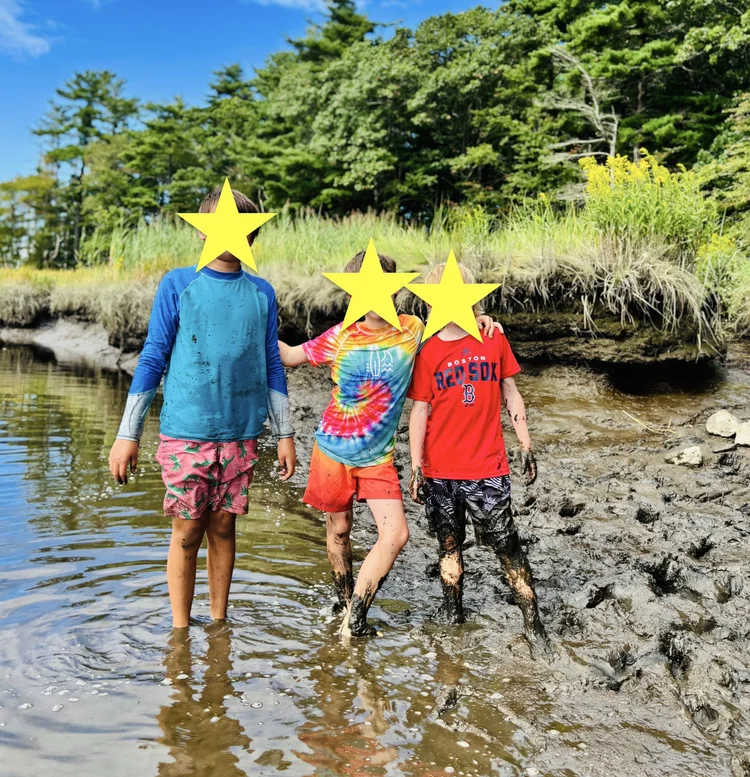 Children posing in a muddy river bank during summer.