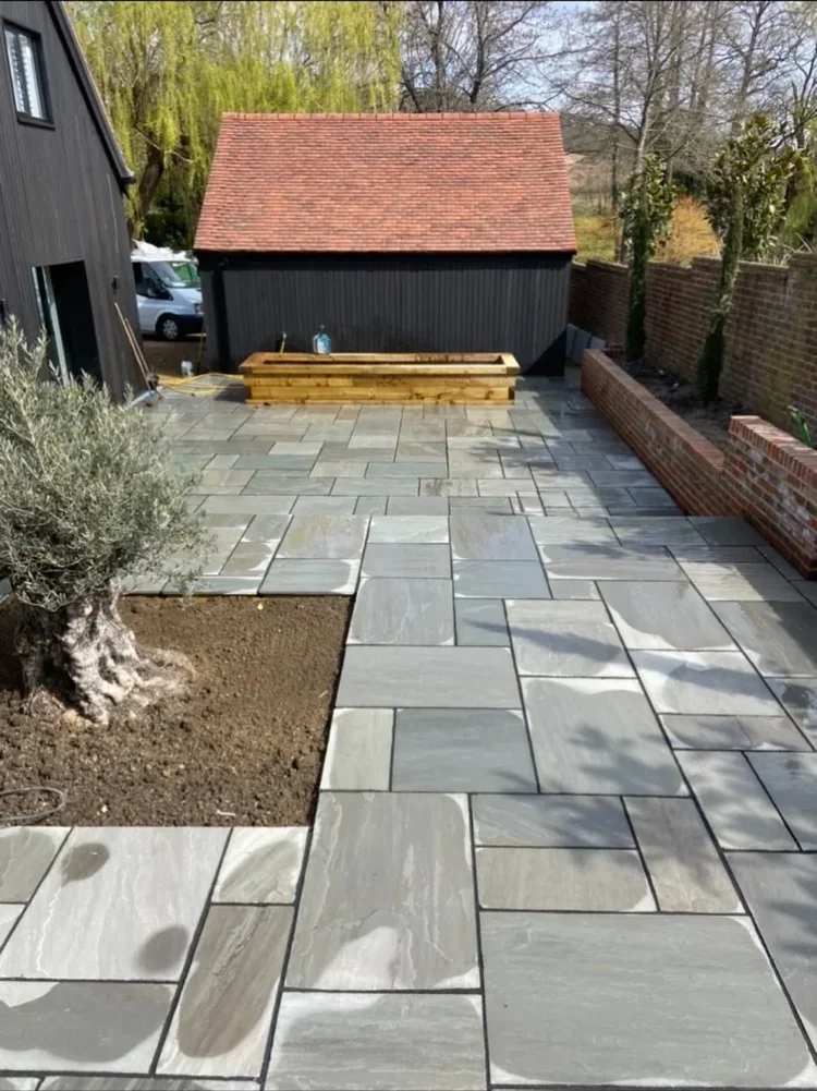 Sandstone patio with brick retaining wall and planter