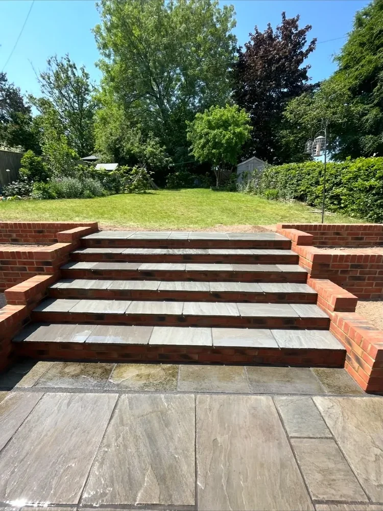 Red brick and stone steps built between a patio and lawn