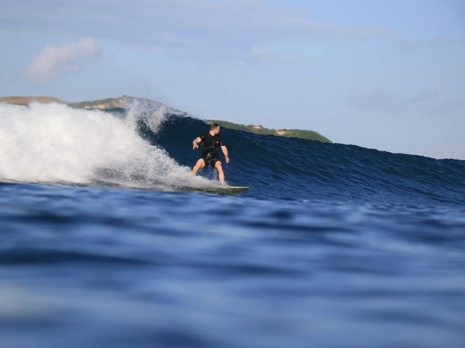 Surfer on a wave at Gerupuk bay, South Lombok