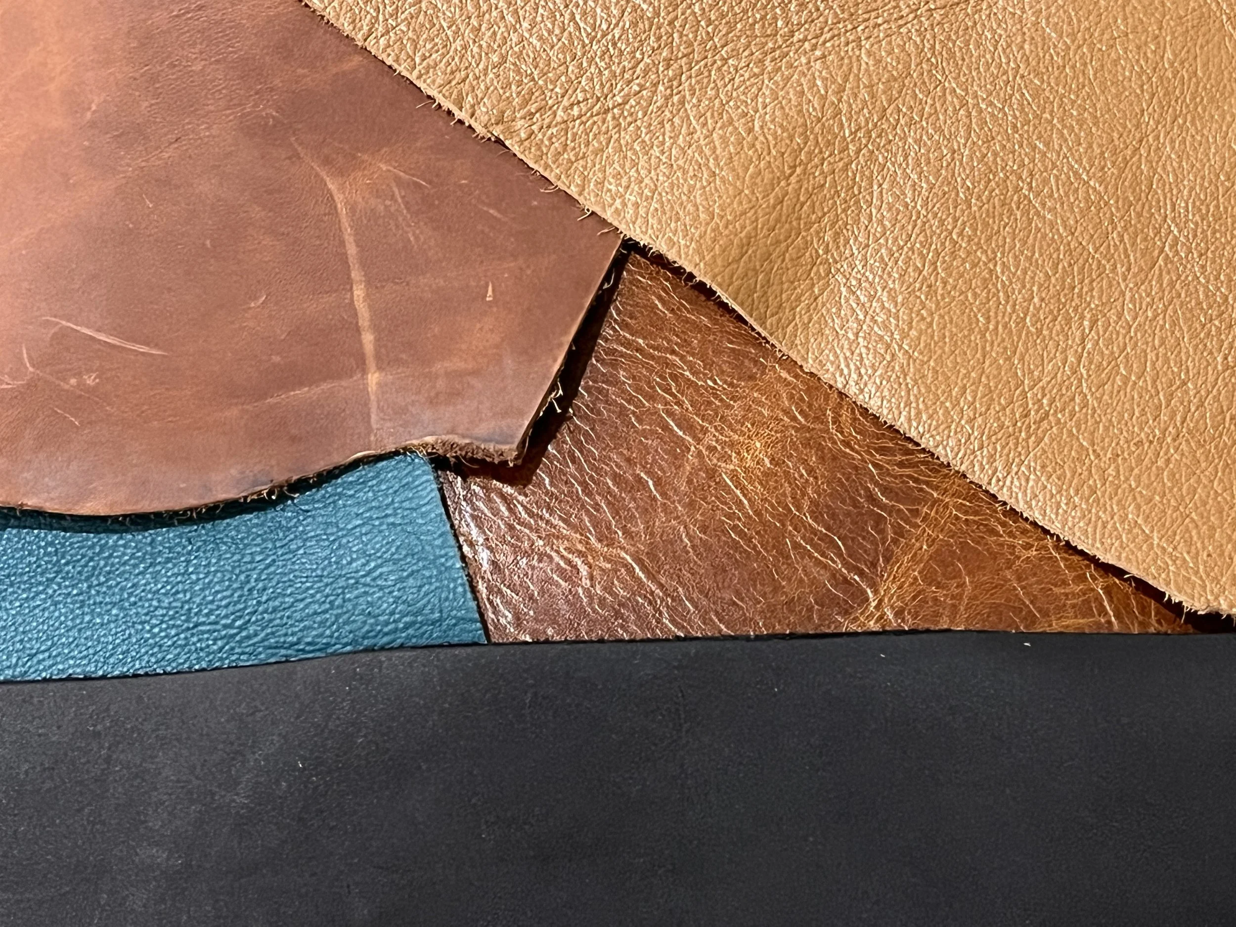 Overlapping leather pieces in tan, brown, teal, and black