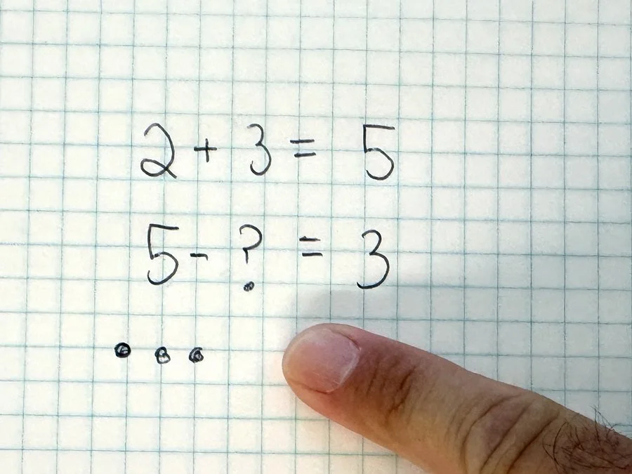 Addition and missing-number subtraction written on the notebook's grid paper