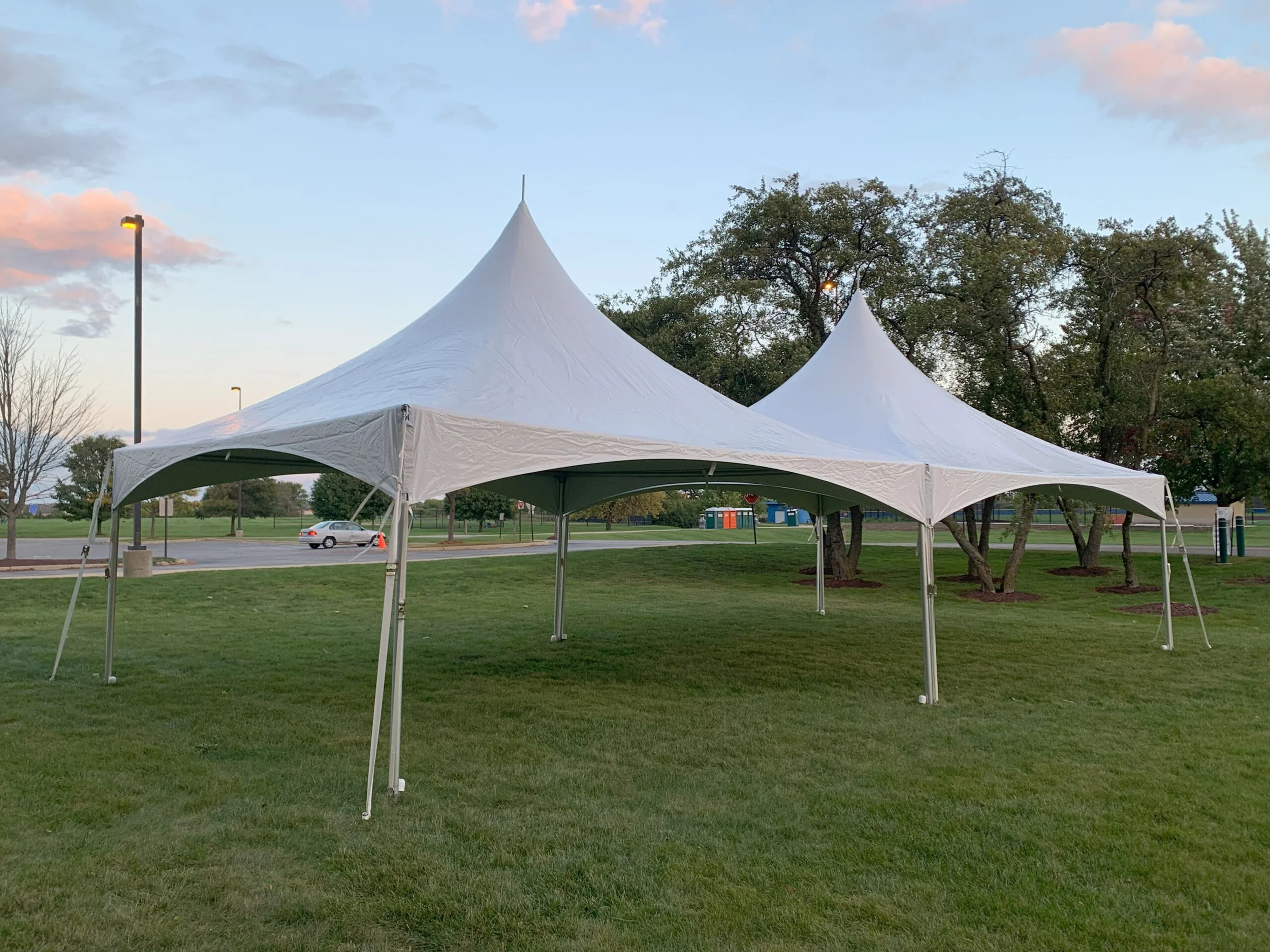 Twilight wedding reception beneath connected white high-peak tents