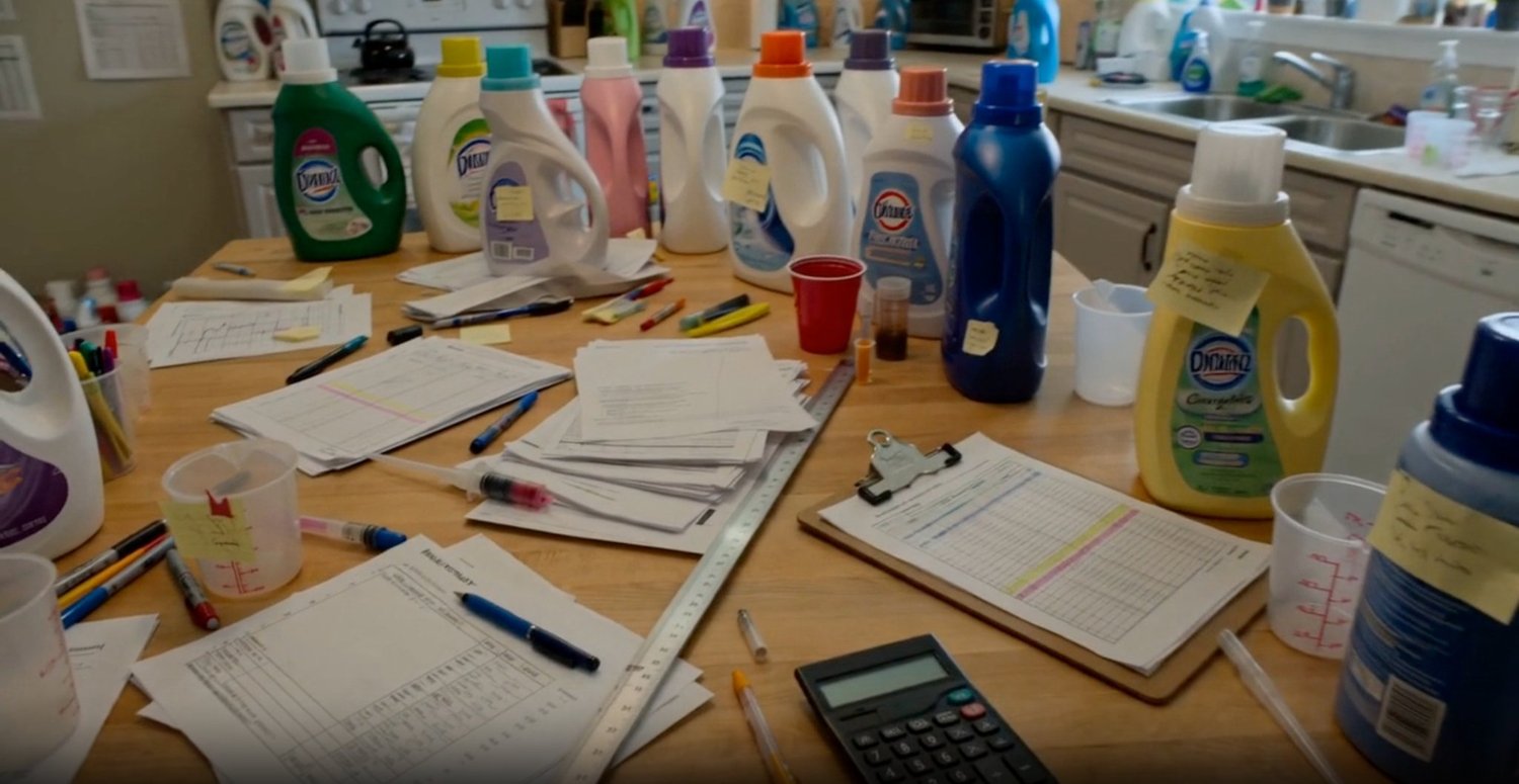Liquid laundry detergent bottles and research papers on a table