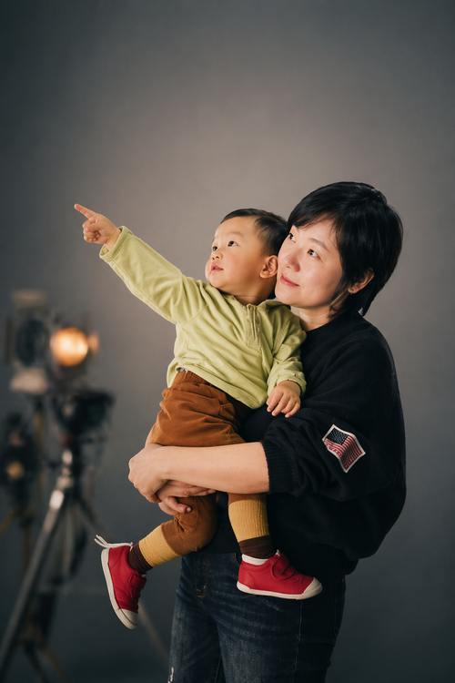 Ling holding a child who points out of the frame