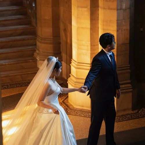 Couple holding hands beside a warmly lit stone staircase
