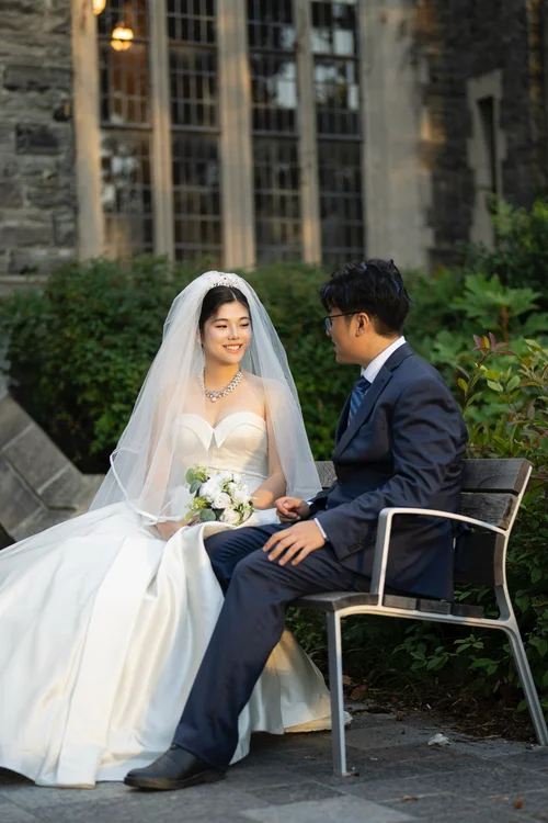 Couple seated together on outdoor chairs beside a stone building