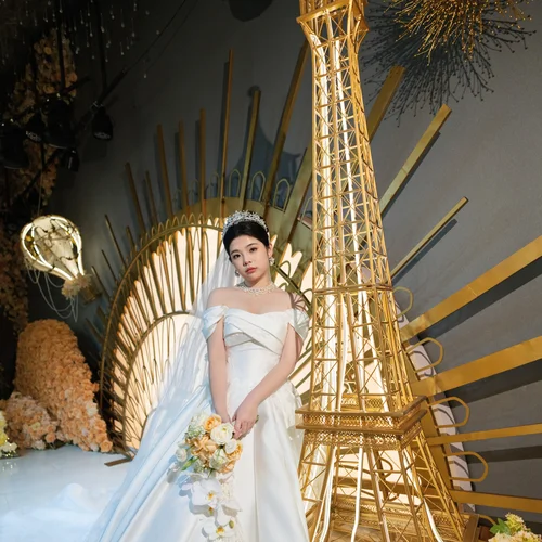 Woman with a bouquet beside a tall gold decorative tower