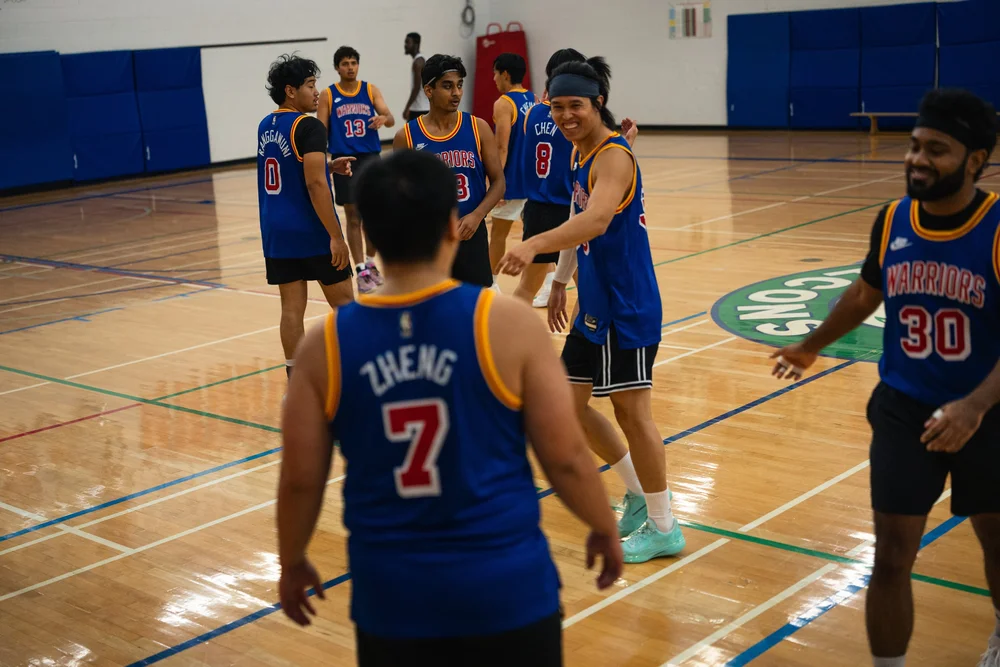 Warriors players smile and extend their hands toward teammates on the court.
