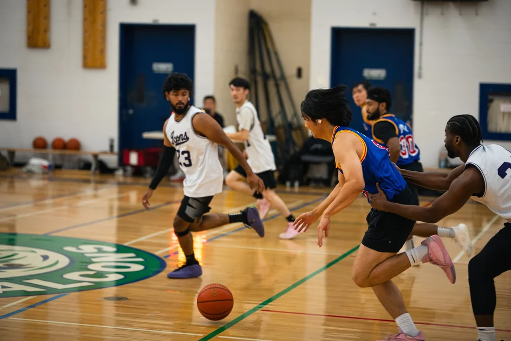 A blue-shirted ball-handler runs up court as white-shirted defenders pursue.