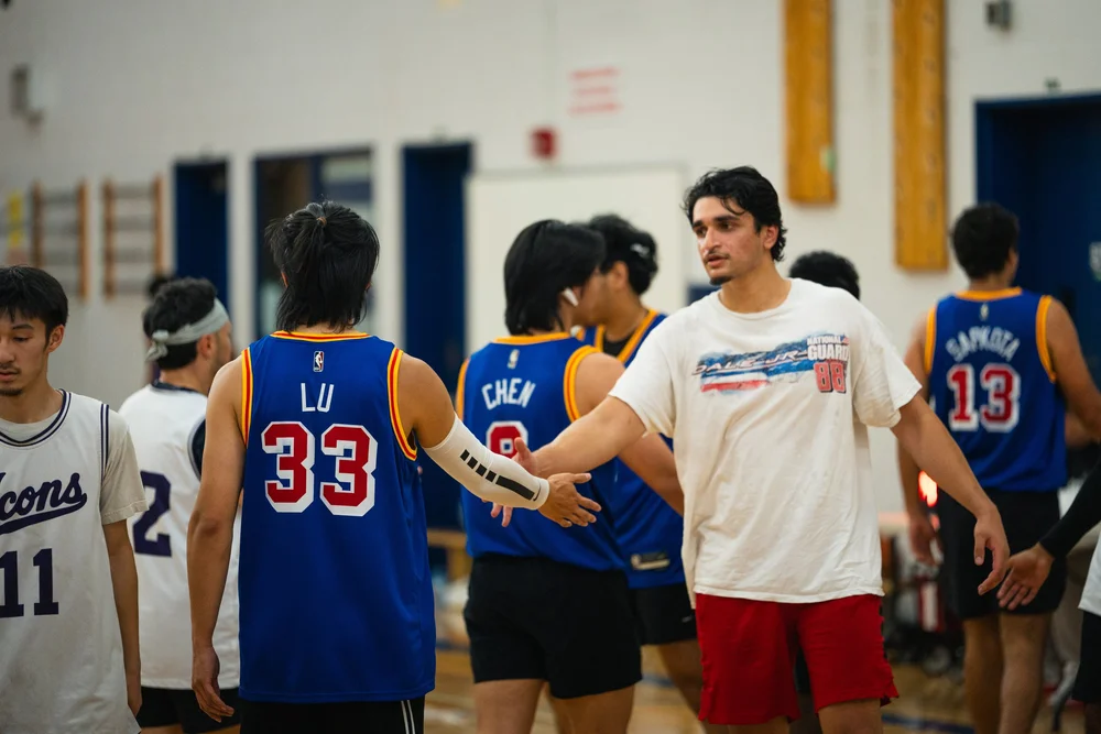 Warriors number 33 shakes hands with a player in an off-white shirt and red shorts.