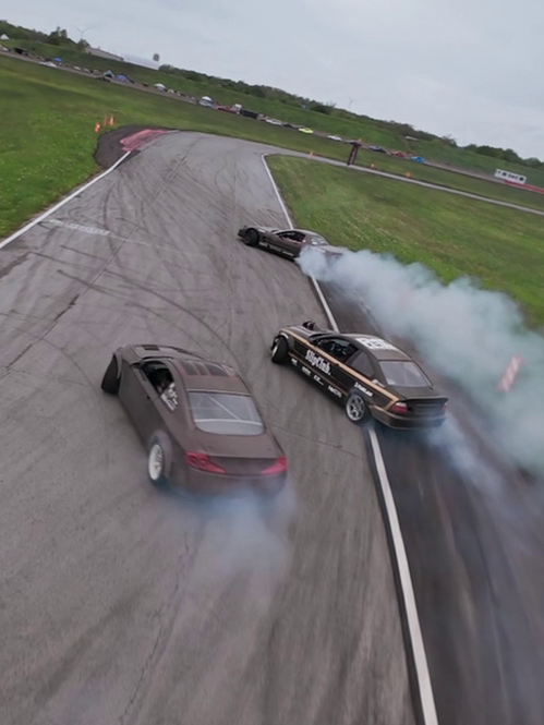 Three cars drifting through tyre smoke, seen from above