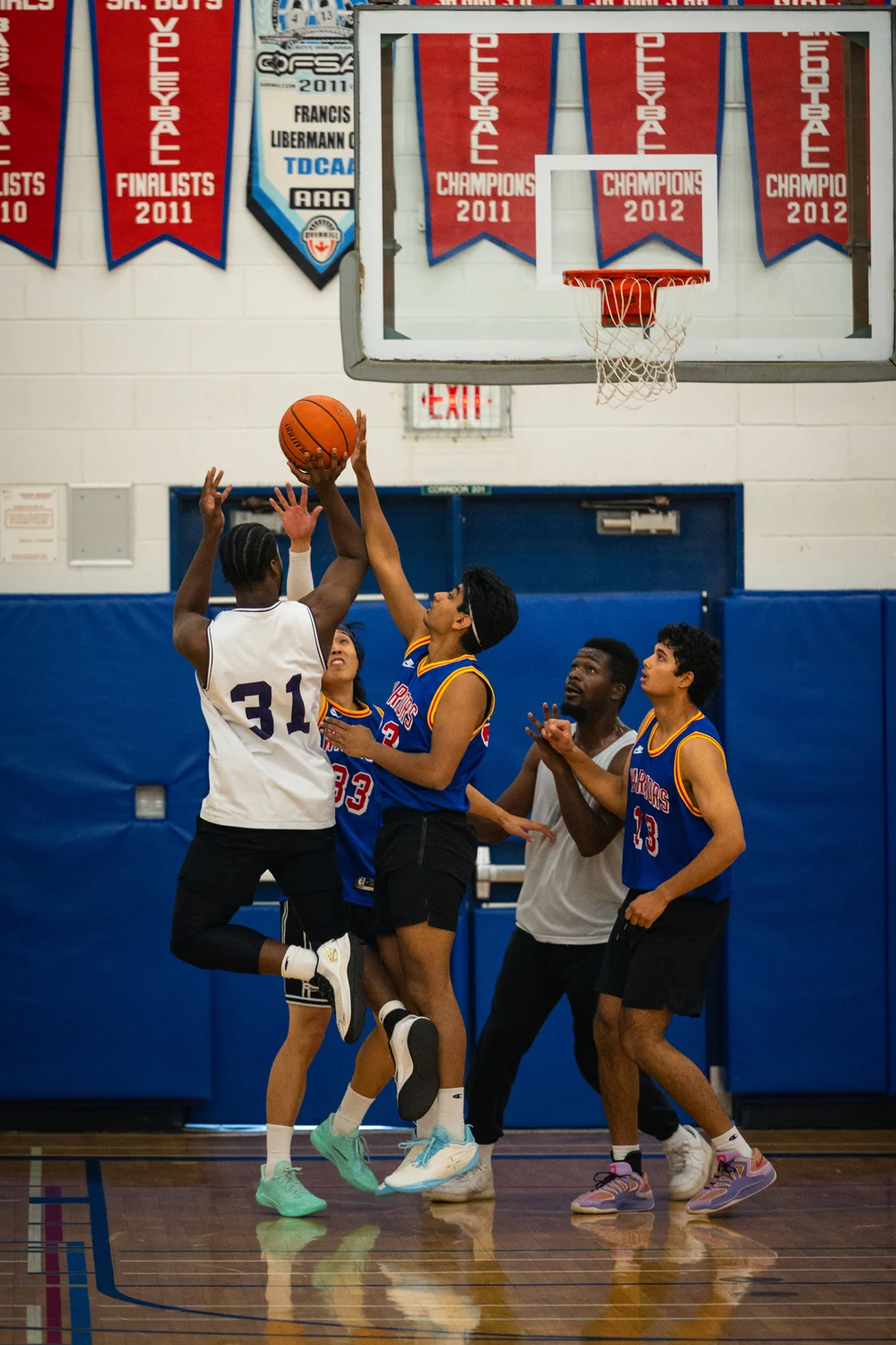 Icons B number 31 holds the ball high as Warriors defenders contest beneath the hoop.