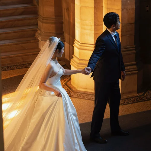 Couple holding hands at the foot of a warmly lit stone staircase