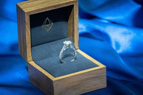 Diamond ring in an open wooden box against blue fabric