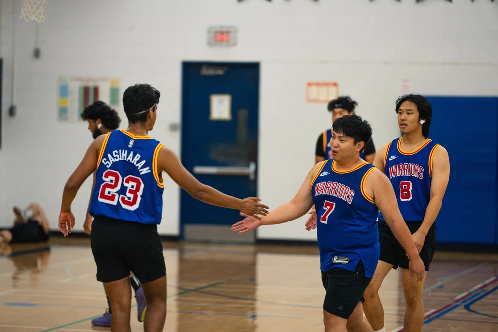 Warriors numbers 23 and 7 extend their hands toward each other, with number 8 behind.