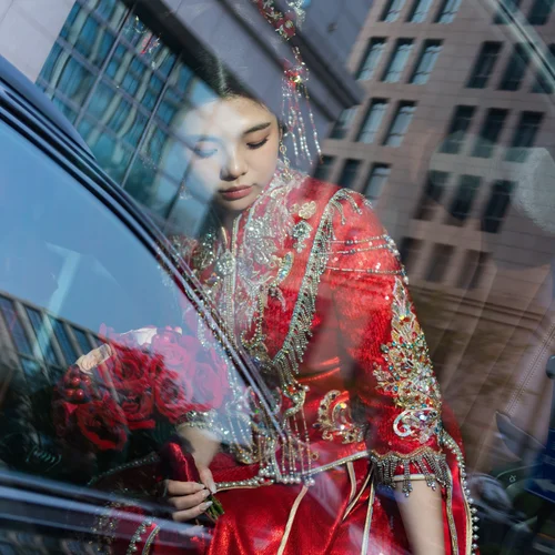 Woman in red embroidered clothing seen through a car window
