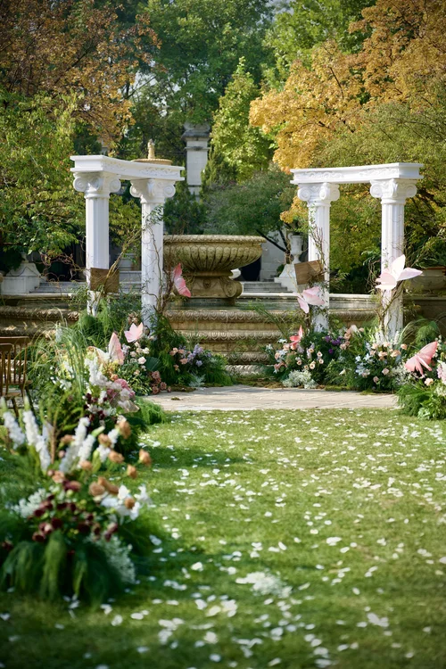 Garden ceremony aisle lined with flowers and white columns