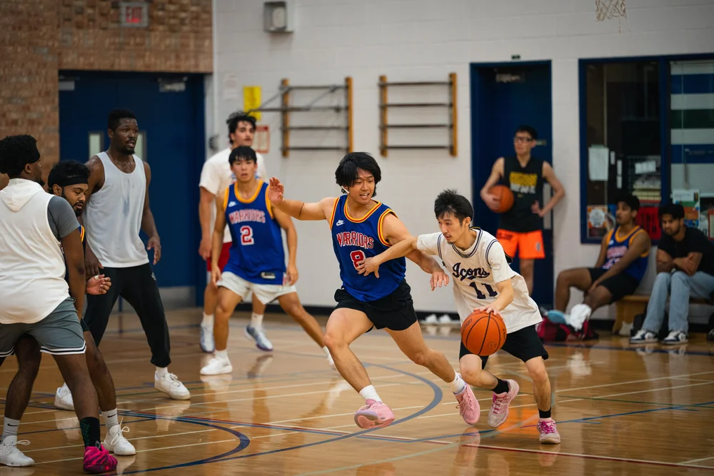 Icons B number 11 dribbles past Warriors number 8 as other players watch.