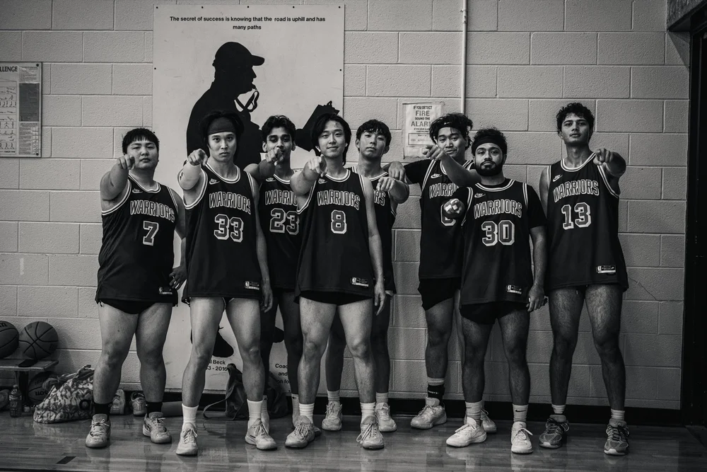 Black-and-white photograph of eight Warriors players pointing toward the camera.