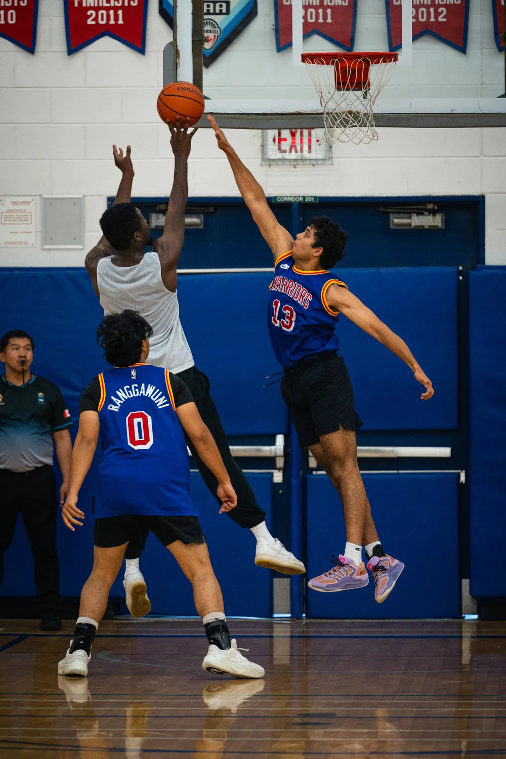 Warriors number 13 jumps with an arm extended toward a white-shirted player’s raised basketball.