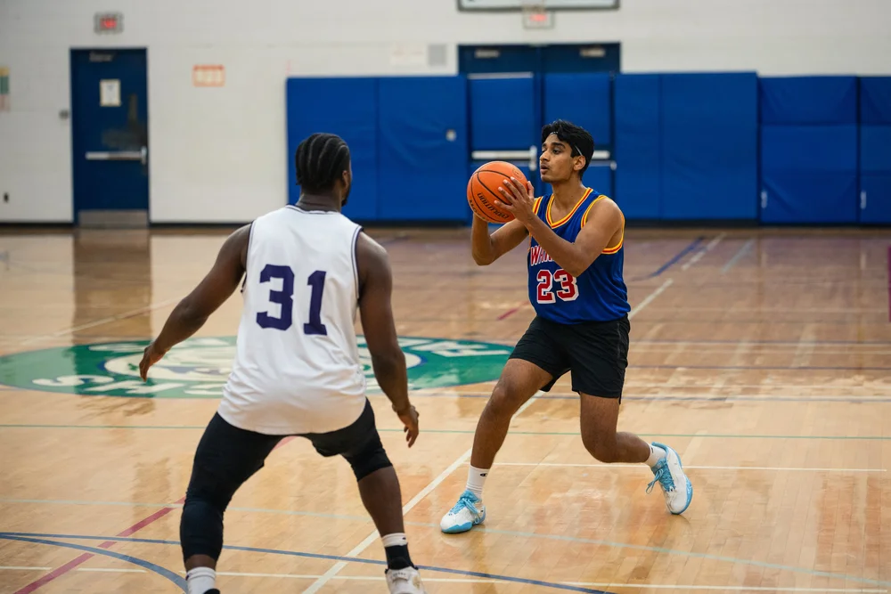 Warriors number 23 holds the ball at chest height while facing Icons B number 31.