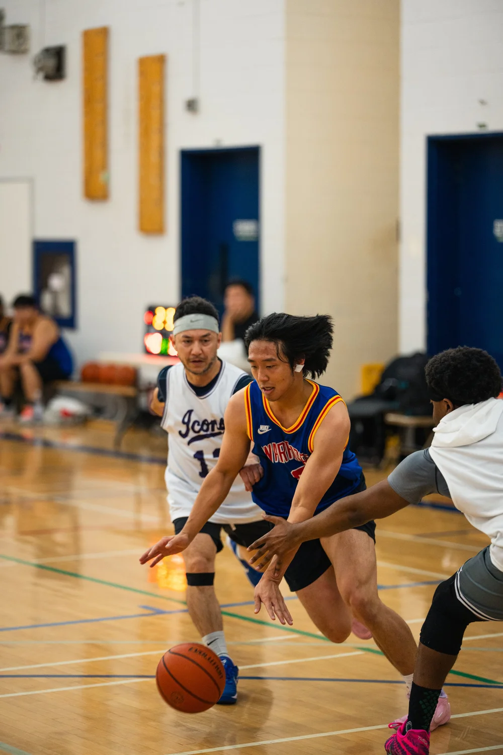 A blue-shirted player dribbles between an Icons defender and another white-shirted player.