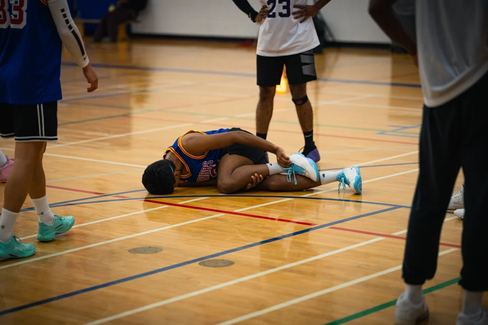 A Warriors player lies on his side on the court, surrounded by standing players.