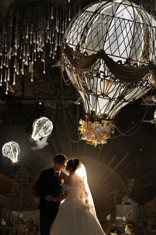 Couple embracing beneath an illuminated globe-shaped ceiling decoration