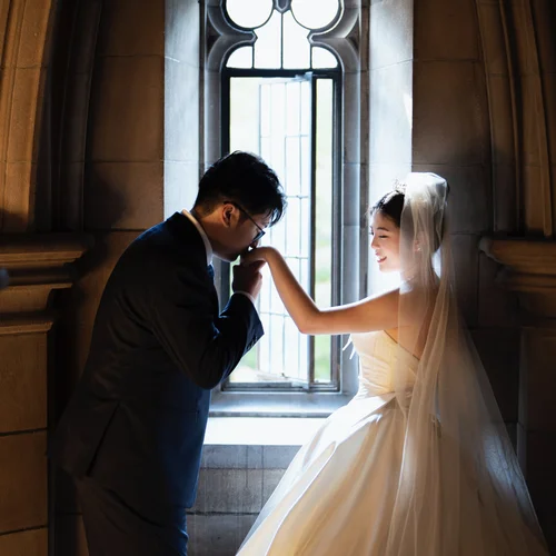 Woman extending her hand to a man beside a tall arched window