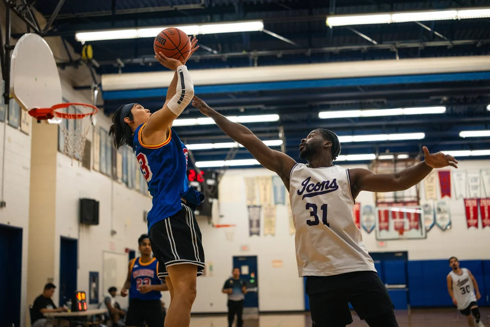 A blue-shirted Warriors player raises the ball near the basket against Icons B number 31.