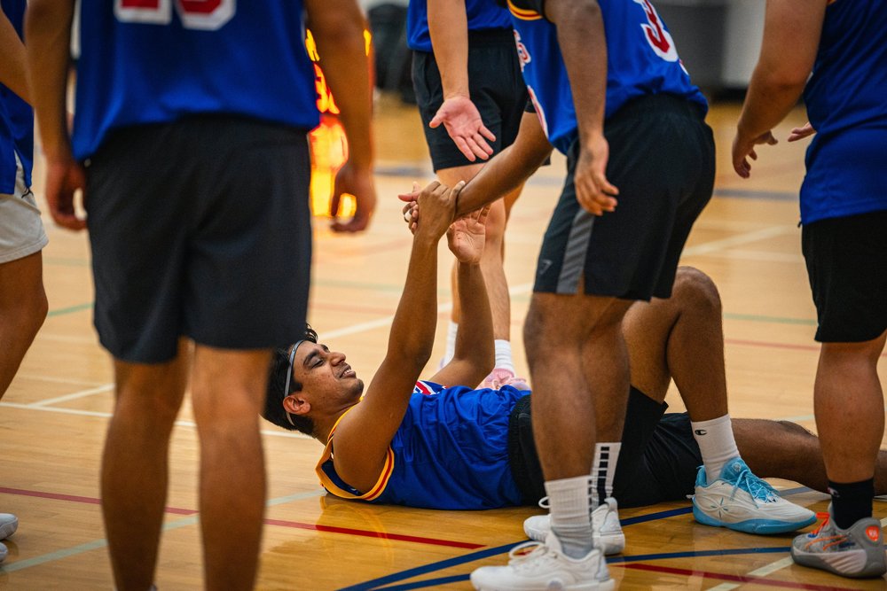 A Warriors player lying on the court clasps a standing teammate’s hand.