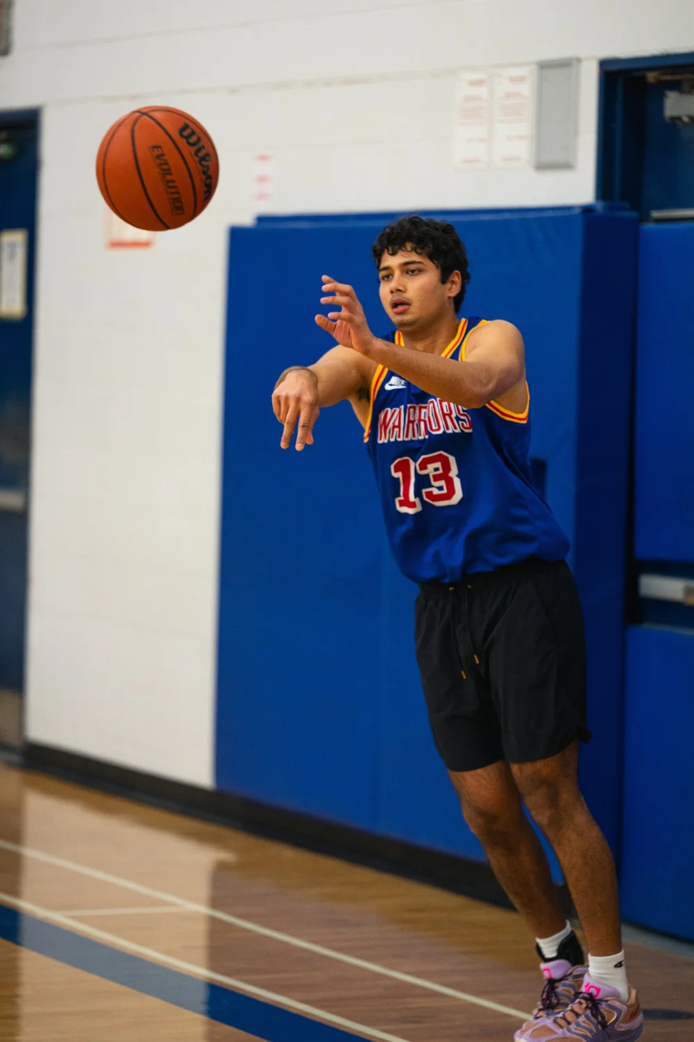 Warriors number 13 passes a basketball, with the ball in the upper-left corner.