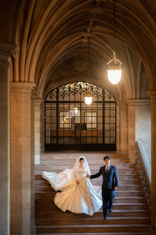 Couple walking down a stone staircase, the white gown sweeping across the steps