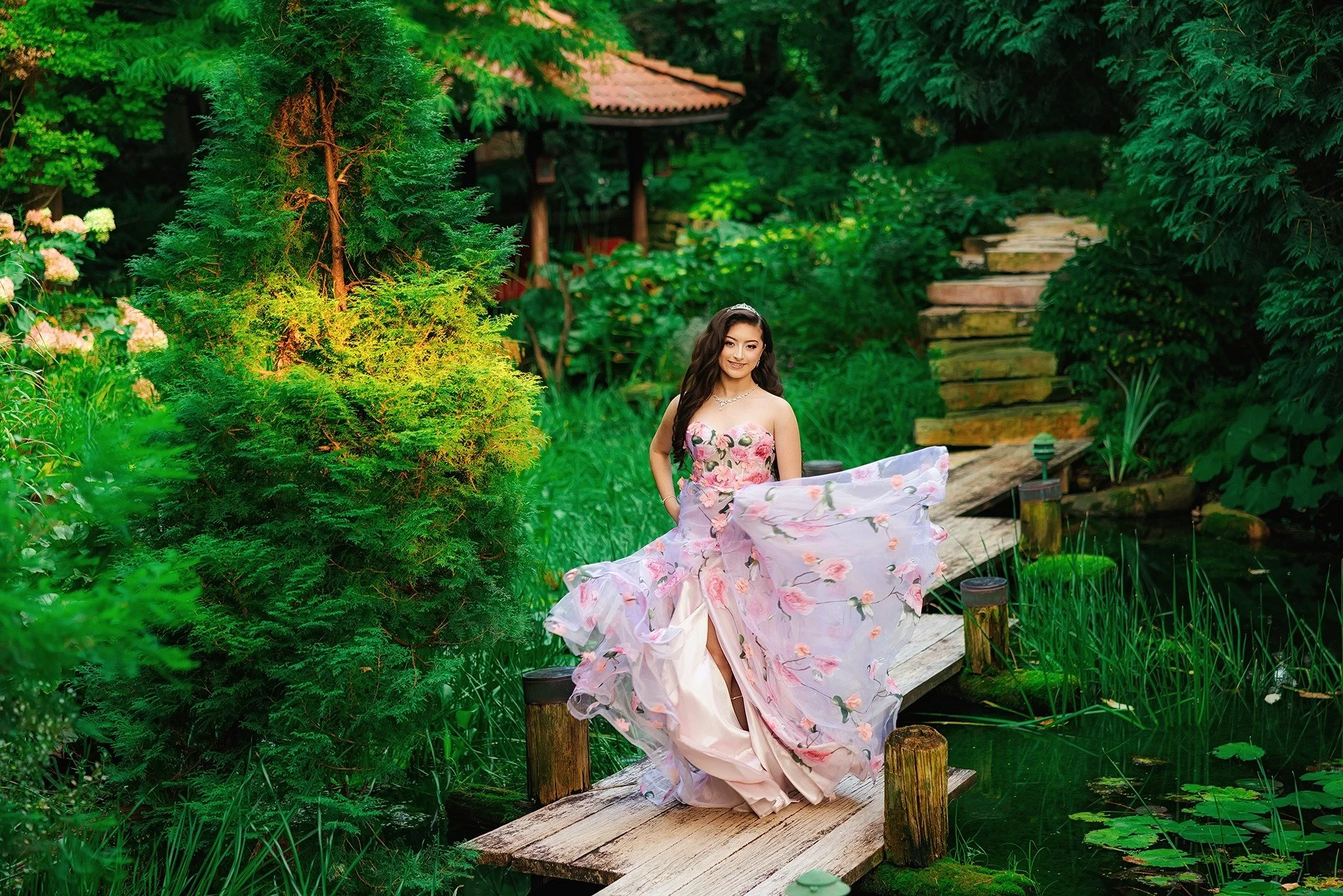 Quinceañera in a lilac gown beside a lush garden pond