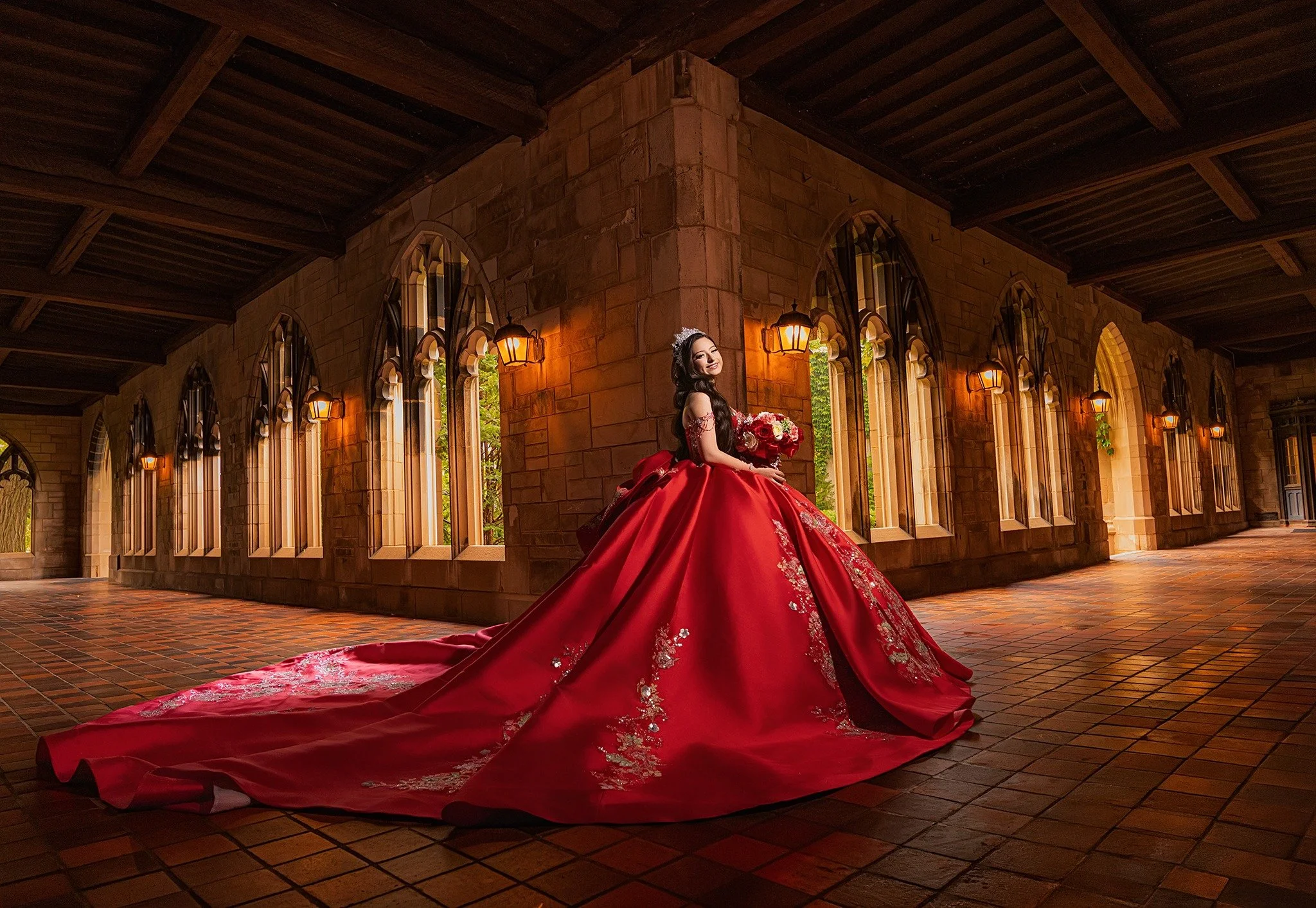 Quinceañera in a red gown photographed inside a dramatic historic hall