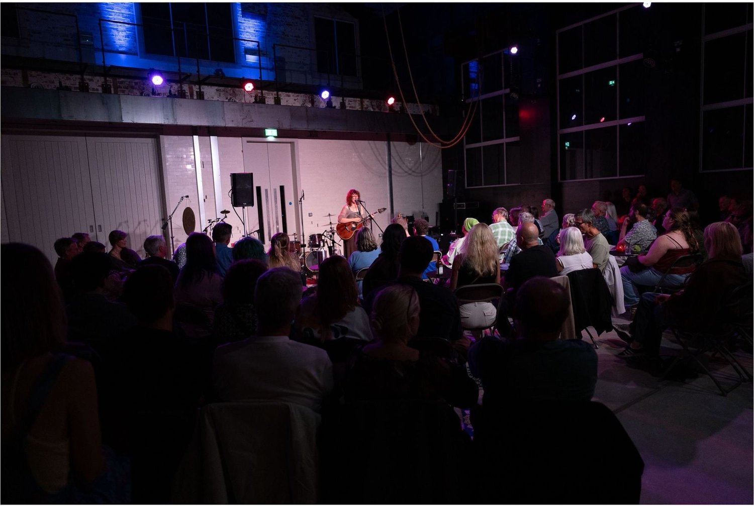 A singer performing on stage to a packed audience in the Main Hall