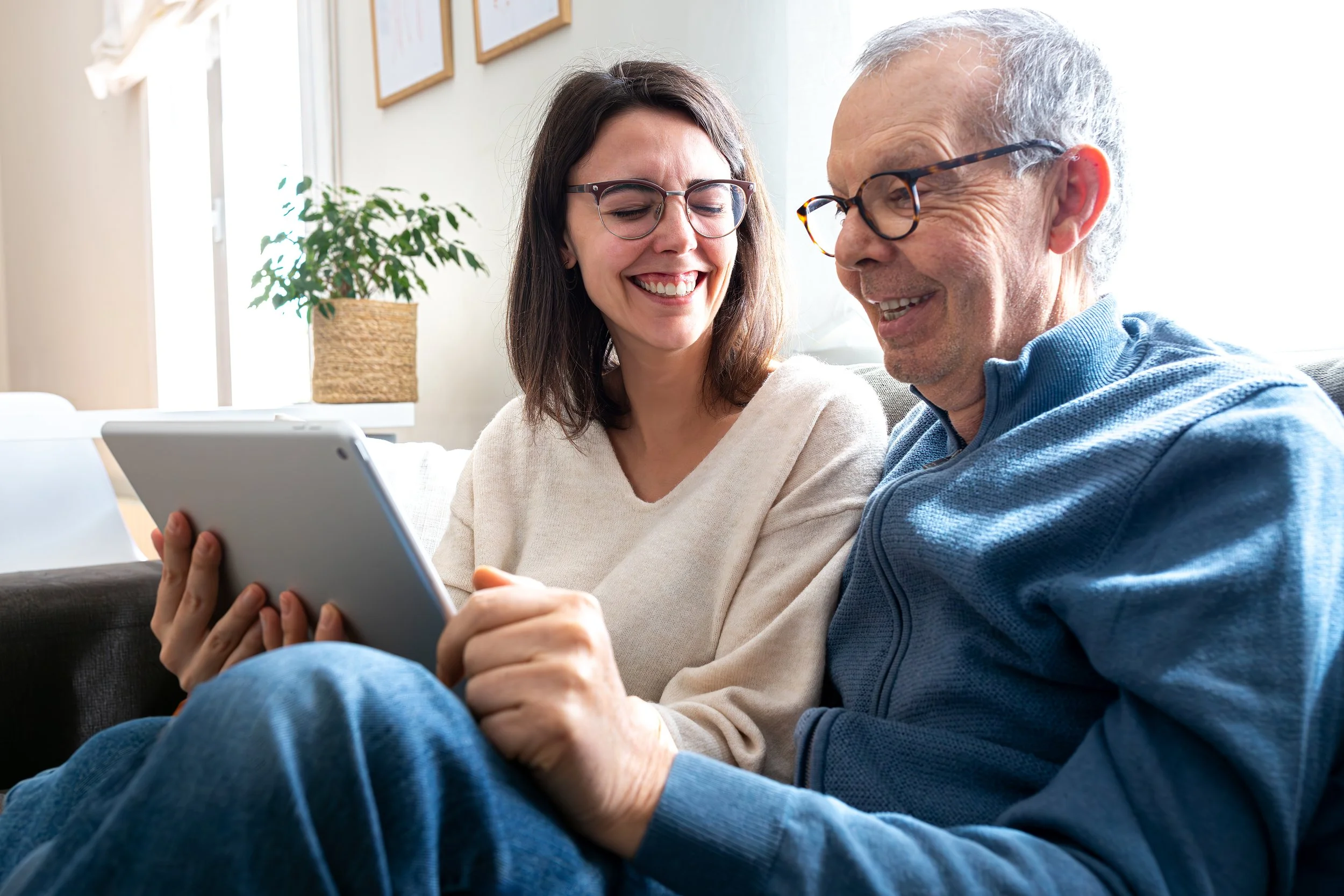 Adult daughter and senior father reviewing care options together on an iPad