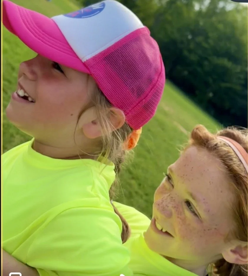Close-up of a smiling GLOW girl in her pink-and-white hat.
