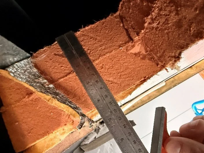 Steel rule measuring the cavity in an opened-up section of brick cavity wall
