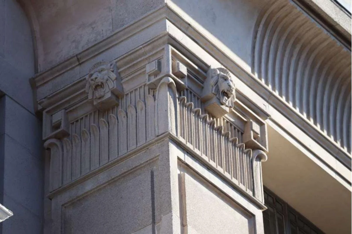 Lion's-head mouldings and fluted pilasters on the cast-stone cornice