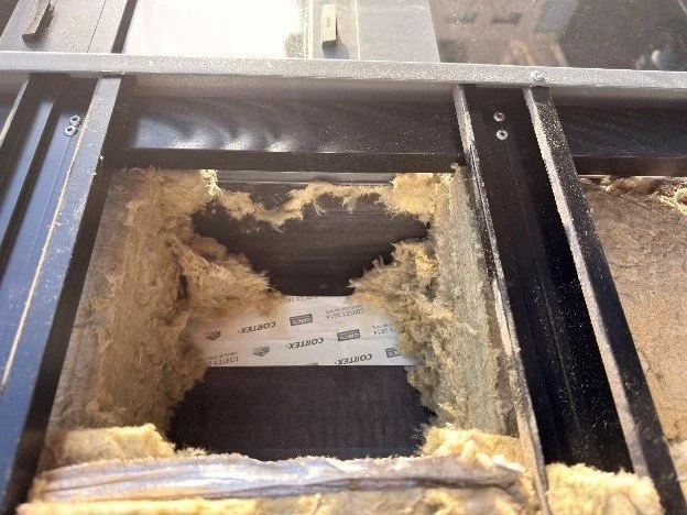 Opening in the rainscreen showing mineral wool insulation and sheathing behind the aluminium sub-frame