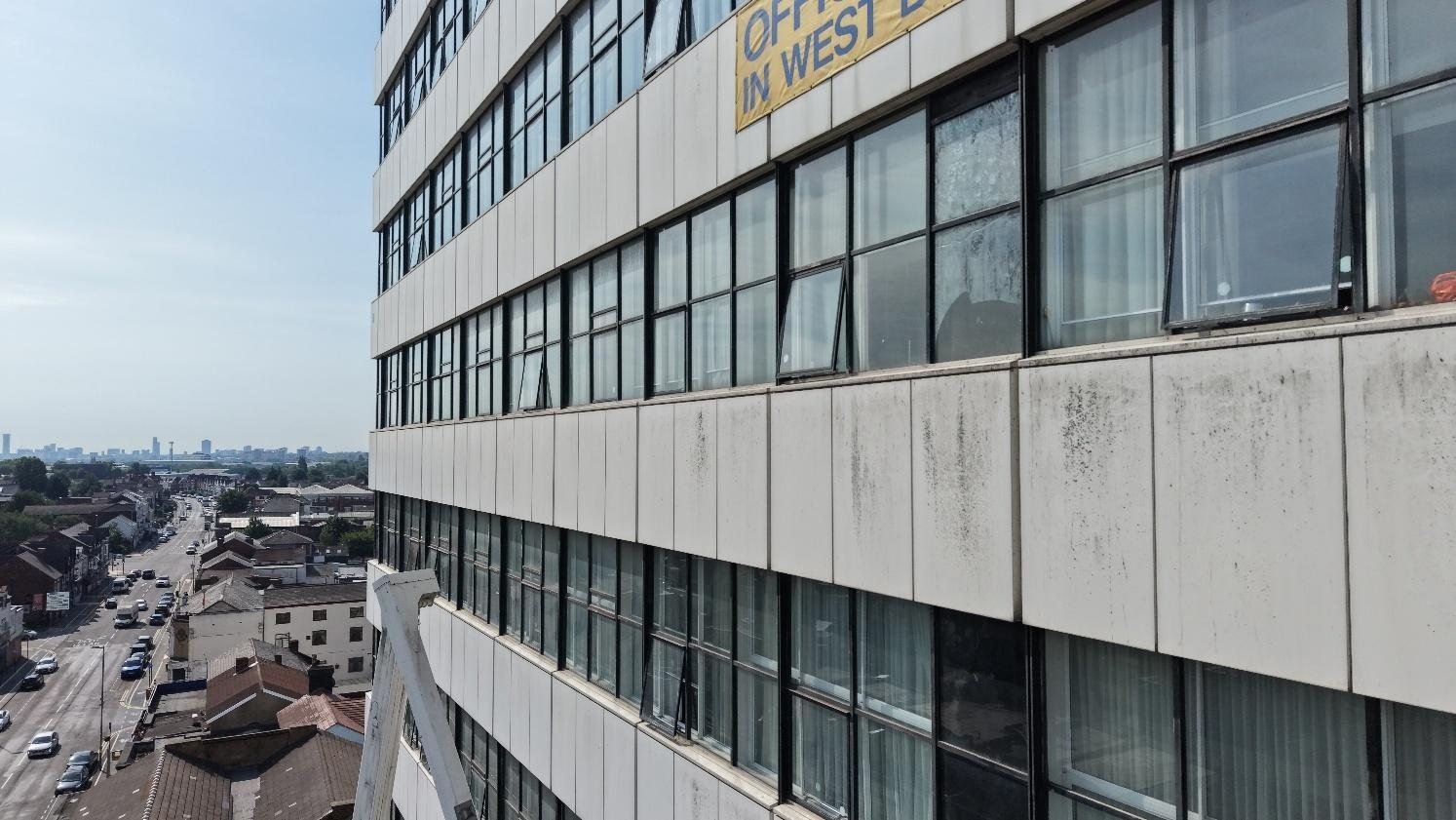 View along the steel panels and ribbon windows of West Plaza from the cherry picker, with the town beyond
