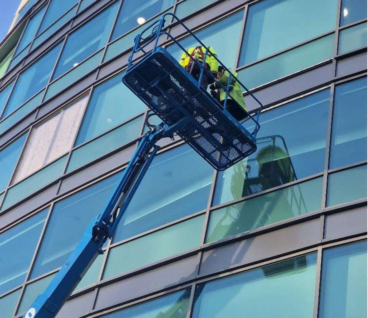 Surveyors on a mobile elevating work platform inspecting the glazed façade