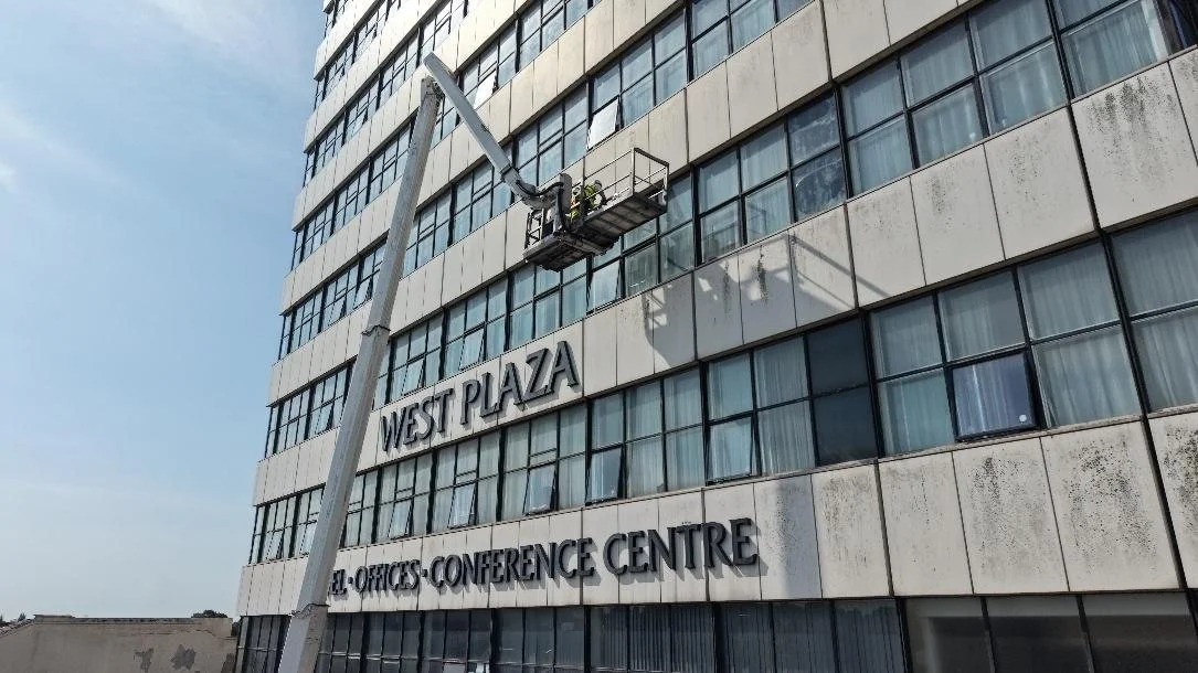 Cherry picker raised against the steel-clad elevation of West Plaza, West Bromwich, during the façade survey