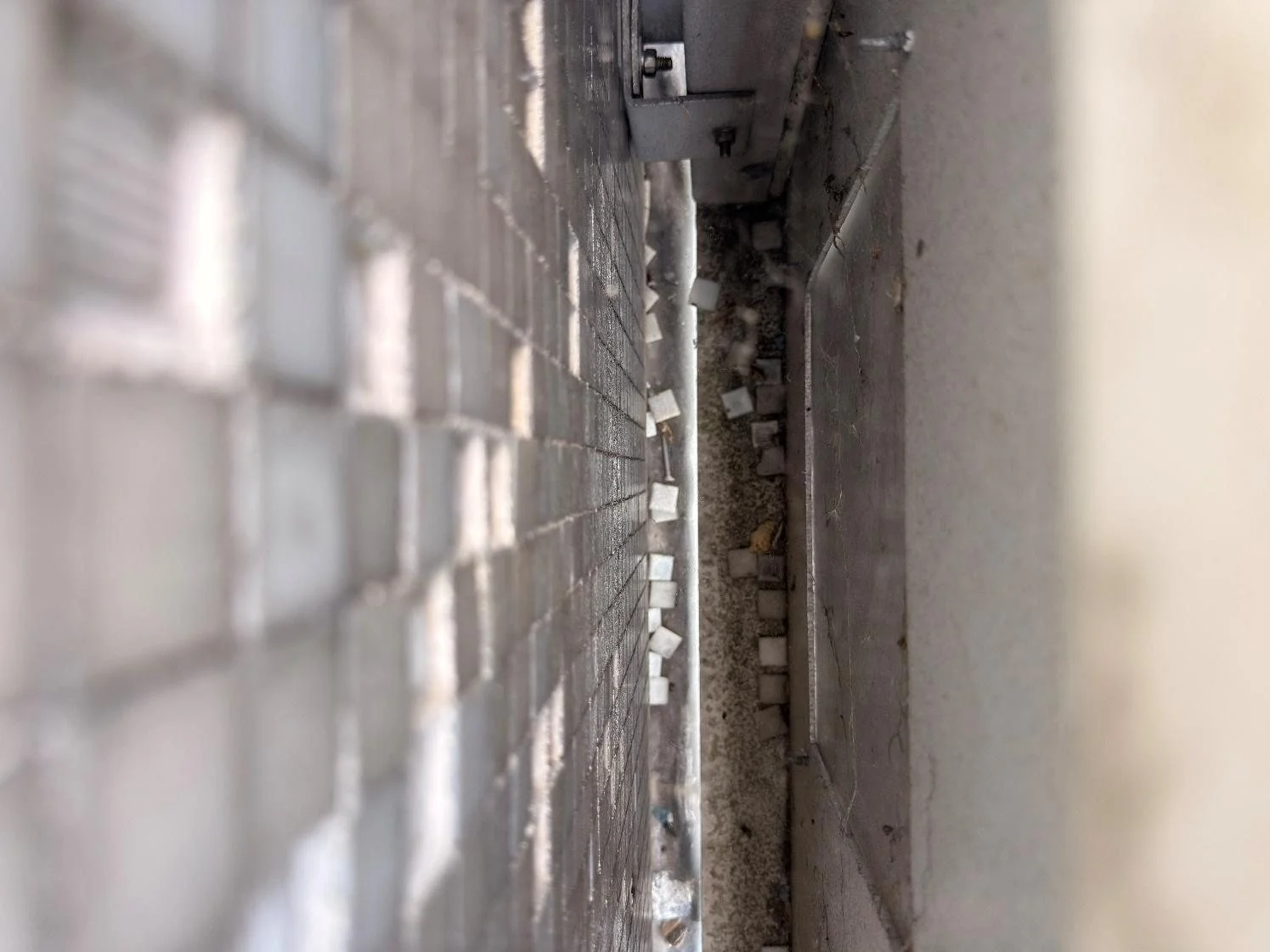 View down the cavity between the steel cassettes and the mosaic tiled concrete wall