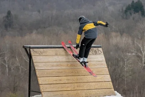 Skier riding a wooden terrain park wall